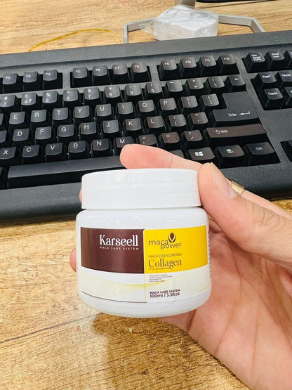 A hand holds a jar labeled with the brand dd54a8-8b, showcasing the Karseell Maca Power Collagen Hair Mask 100ml (Pack of 2), in front of a computer keyboard on a wooden desk. The jar’s white and yellow label indicates its durable construction, making it ideal for maintaining quality over time.